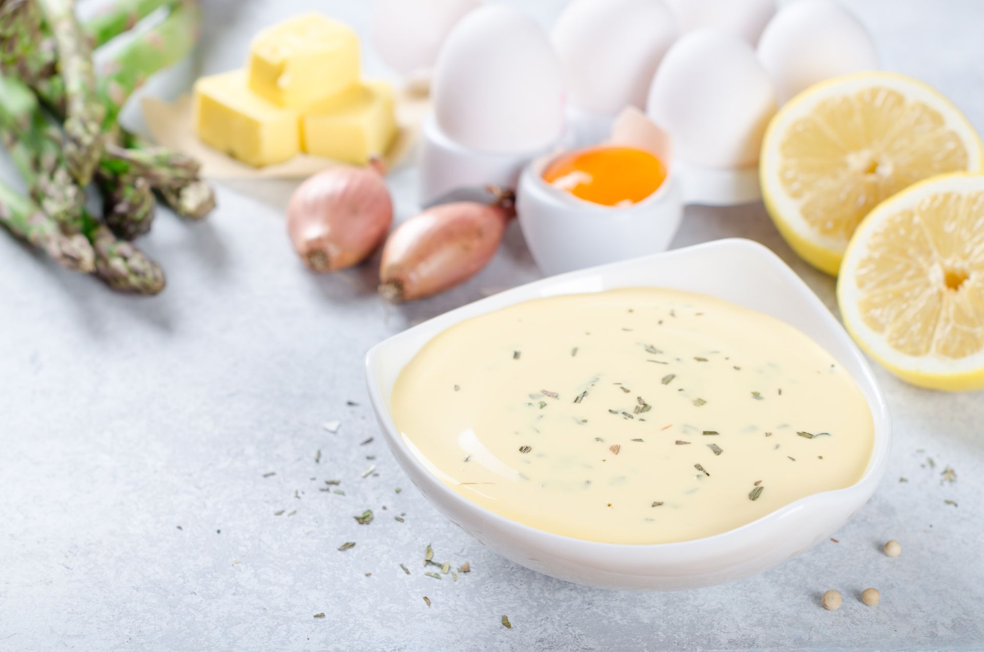 Basic french sauce bearnaise in a white bowl with ingredients, b